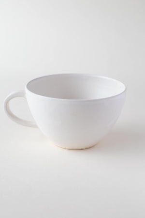 A handthrown ceramic tea cup in our Kinship Collection off-white glaze.