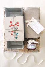 A gift box including an herb planter, seed postcards, a lavender honey flower and a linen apron