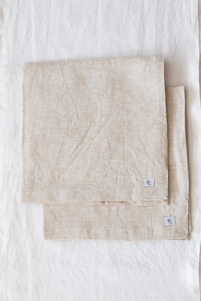 A set of four 100% linen dinner napkins in neutral tones.